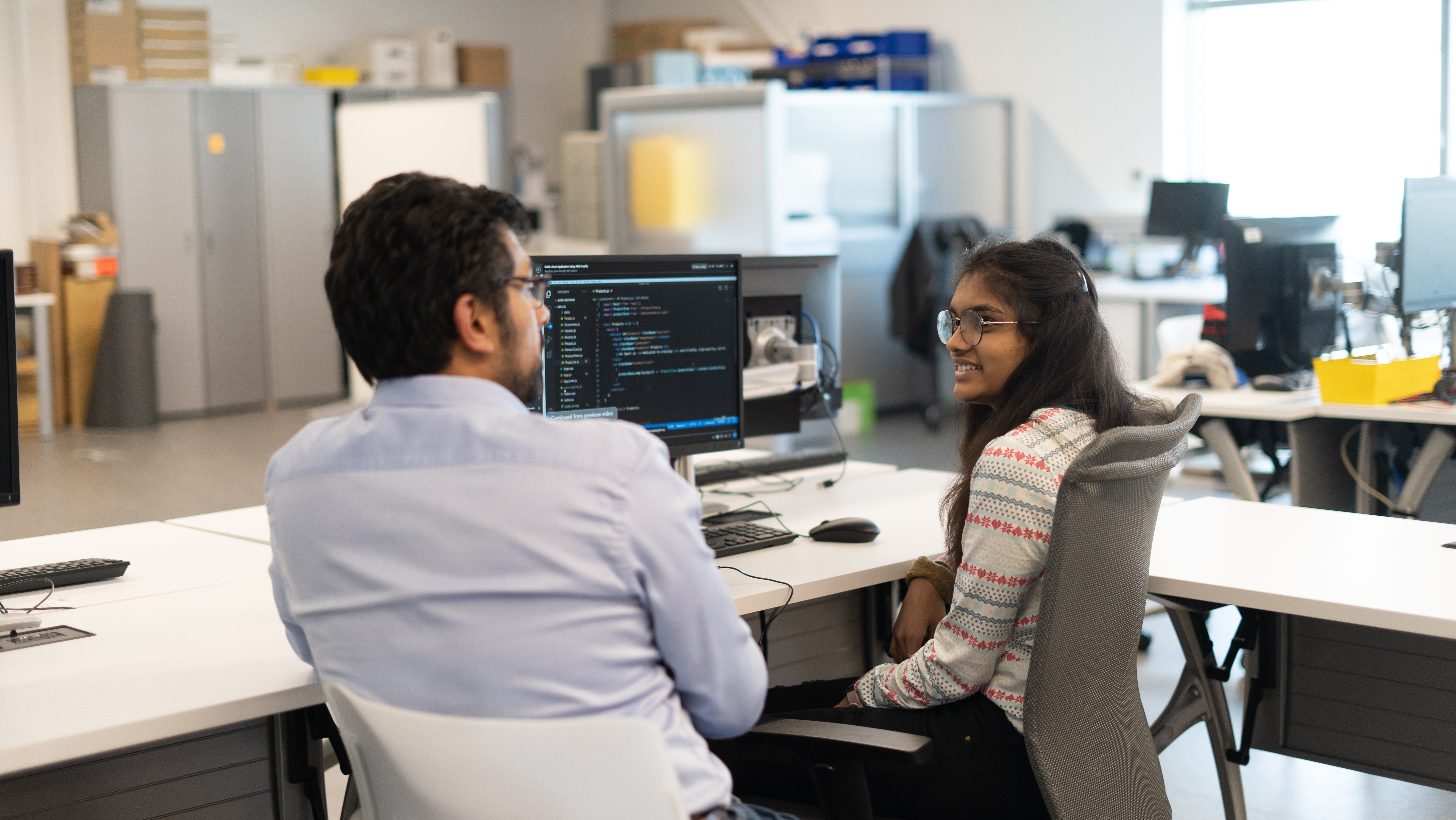 Two colleagues discussing work at a workstation